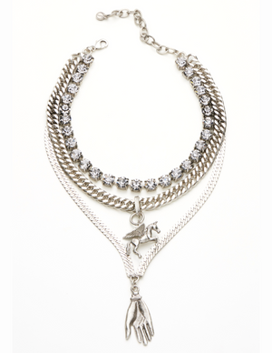 A triple layered necklace with a mix of metallic finishes and a charm in the shape of a bird.