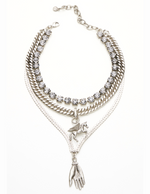 A triple layered necklace with a mix of metallic finishes and a charm in the shape of a bird.